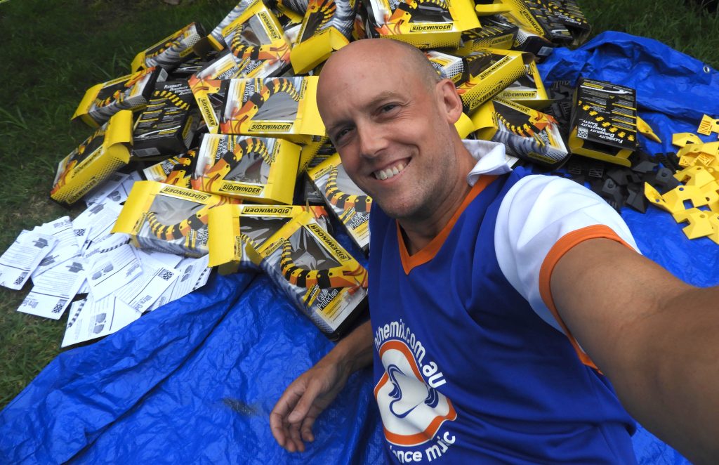 Dan Monceaux lies on a tarpaulin among boxes of safety products used to create his sculpture, "Is it safe?"